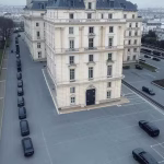 Daniel Estulin: The Controversial Investigator Who Exposed the Bilderberg Group to the World Aerial view of luxury European hotel with security cordon and black vehicles, mysterious elite gathe