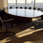 Como ser convidado para o Bilderberg: Por dentro do processo de seleção ultraexclusivo Moderna sala de conferências com mesa circular, cadeiras vazias dispostas para uma reunião diplomática de alto nível,