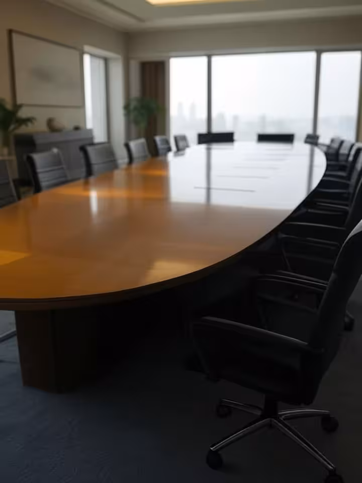 Professional conference room setup with round table discussion, empty chairs arranged for high-level